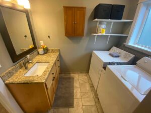 A clean and organized laundry room combined with a bathroom vanity, showcasing the detailed cleaning by E-N-S Home Cleaning Solutions, LLC in Lewiston, ID.