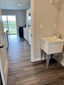A freshly cleaned laundry and utility room featuring a sink and wet floor, indicating a professional cleaning service by Cedar Cleaners LLC in Cedar Rapids, IA.