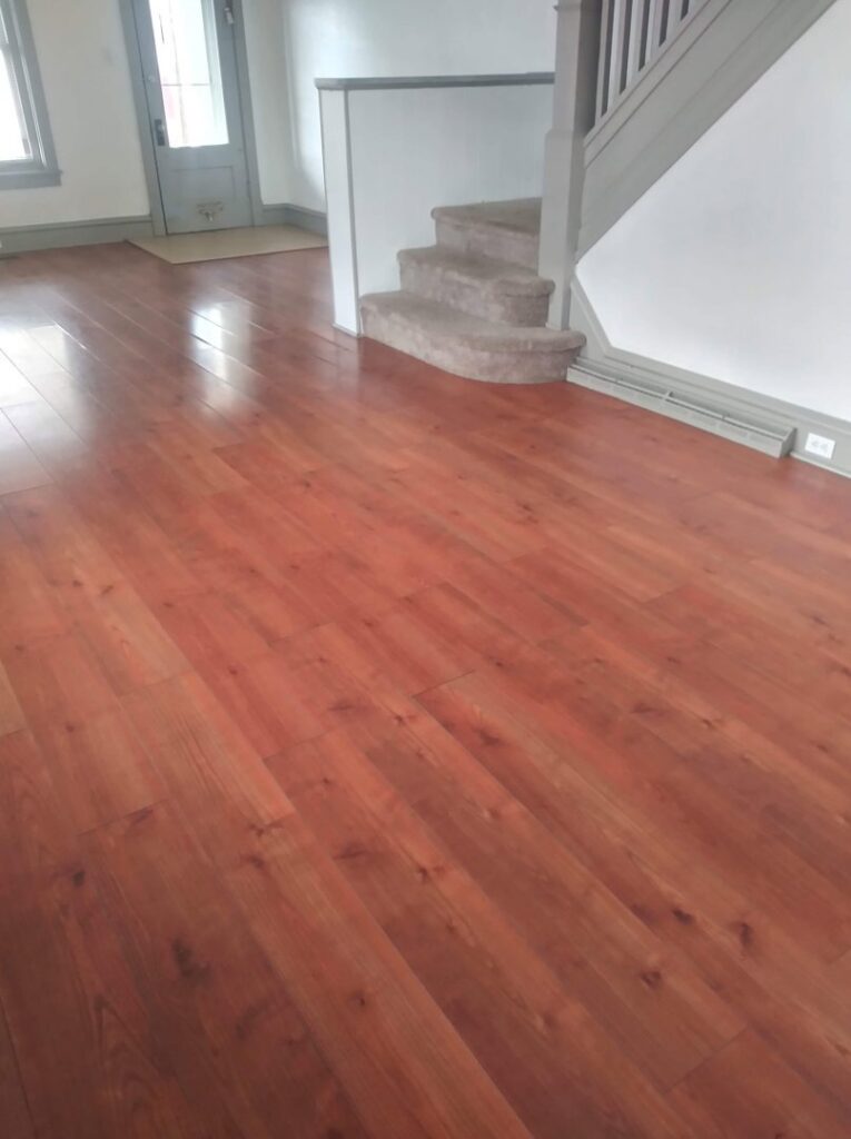 A clean living room with shiny hardwood floors and a carpeted staircase after professional cleaning by Rebeccas Customized Cleaning LLC in Reading, PA.