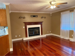 A freshly cleaned living room with polished hardwood floors and a fireplace, provided by In Between Clean 2 in Greeneville, TN.