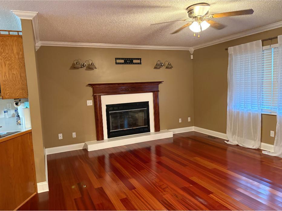 A freshly cleaned living room with polished hardwood floors and a fireplace, provided by In Between Clean 2 in Greeneville, TN.