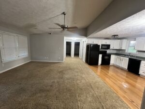 A clean living room with carpet and kitchen with gleaming hardwood floors by Treadway's Cleaning Services in Spencer, IN