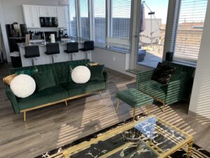 A clean living room and kitchenette area with modern green furniture, showcasing the pristine results from Faye Cleaning Service LLC in Ankeny, IA.