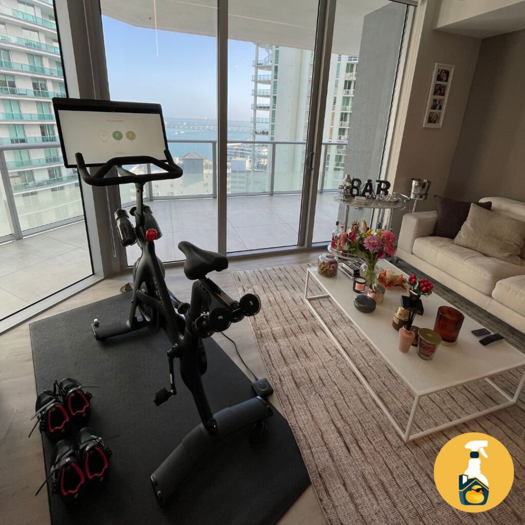 A clean living room featuring a Peloton bike and white sofa, tidied by The Prime Cleaner in Miami, FL.