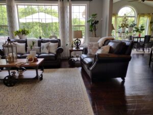 A spacious and clean living room with dark leather sofas, a patterned rug, and large windows, reflecting the excellent cleaning service of Rivas Molina's Cleaning LLC in Dundalk, MD.