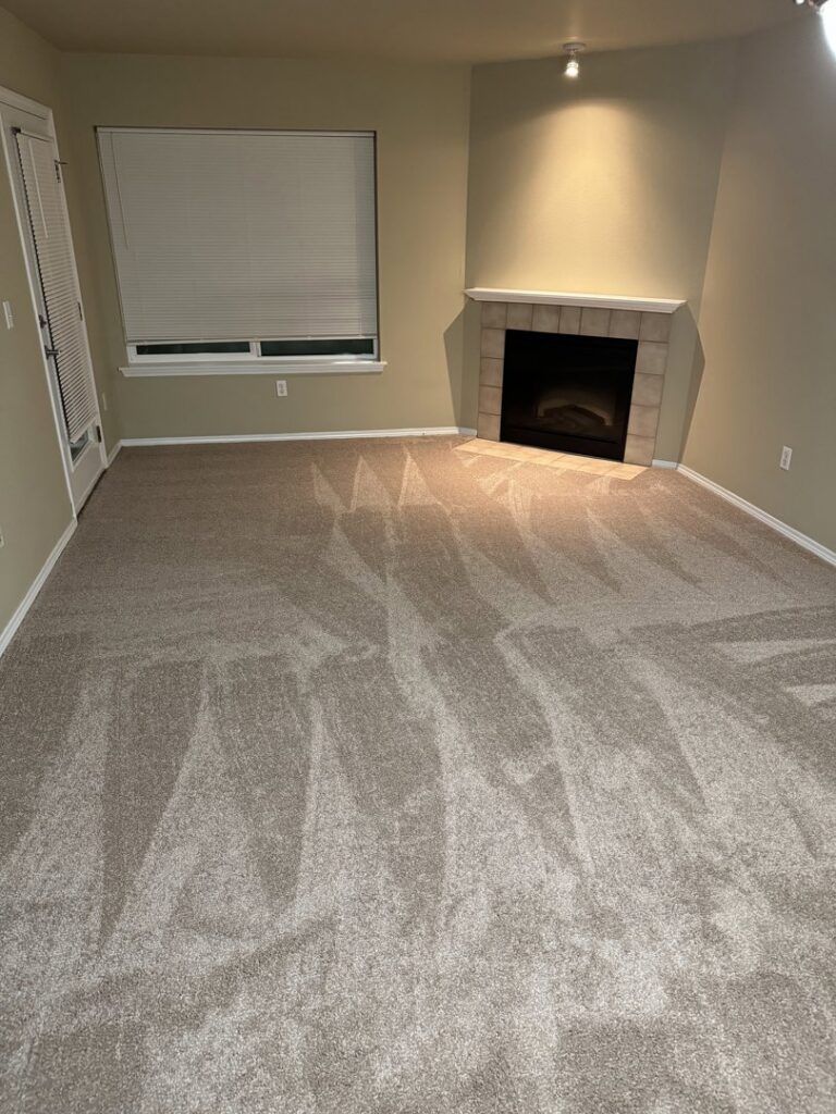 A clean living room with a fireplace and freshly vacuumed carpet after house cleaning by Nannie Needs LLC in Kent, WA.