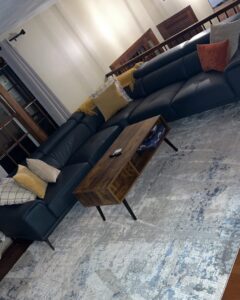 A clean and tidy living room featuring a large sectional sofa and a patterned rug, cleaned by Make It Shine in Worcester, MA