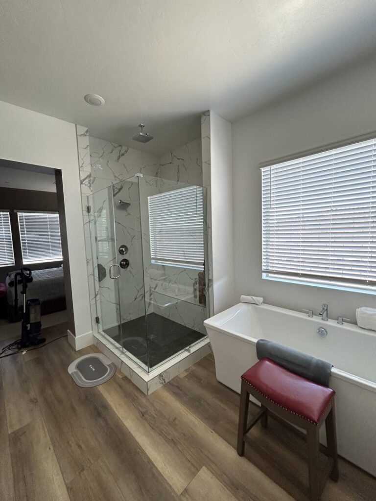 A clean master bathroom with a large glass shower and freestanding tub, showing the results of JG Clean Solutions in Henderson, NV.