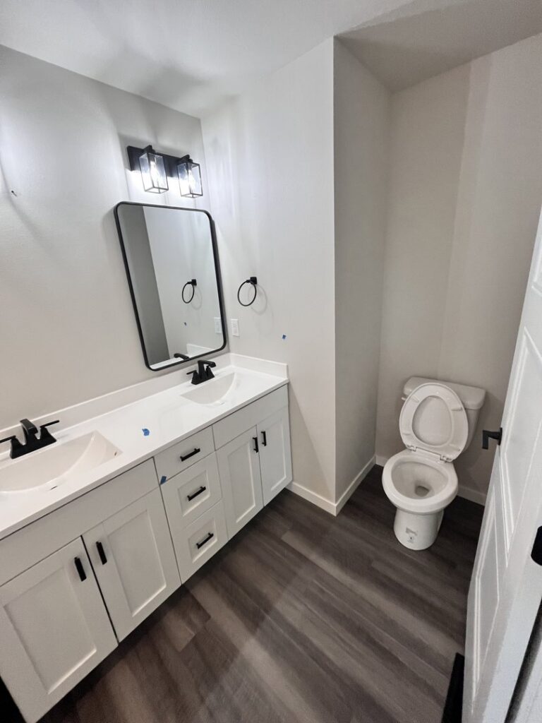 A sparkling clean, modern bathroom with a double vanity and wet floor, demonstrating a thorough cleaning by Cedar Cleaners LLC in Cedar Rapids, IA.