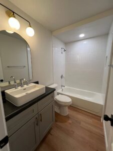 A pristine, modern bathroom with a white vanity, vessel sink, and tiled shower, expertly cleaned by Krys Cleaning in Oklahoma City, OK.