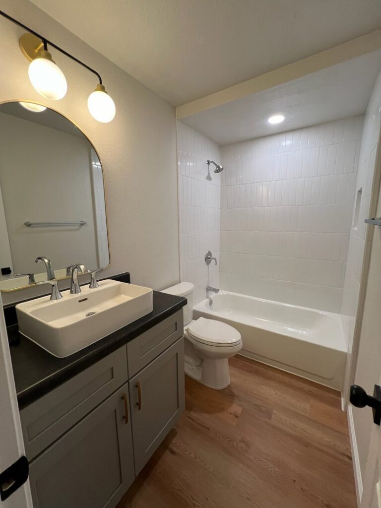 A pristine, modern bathroom with a white vanity, vessel sink, and tiled shower, expertly cleaned by Krys Cleaning in Oklahoma City, OK.
