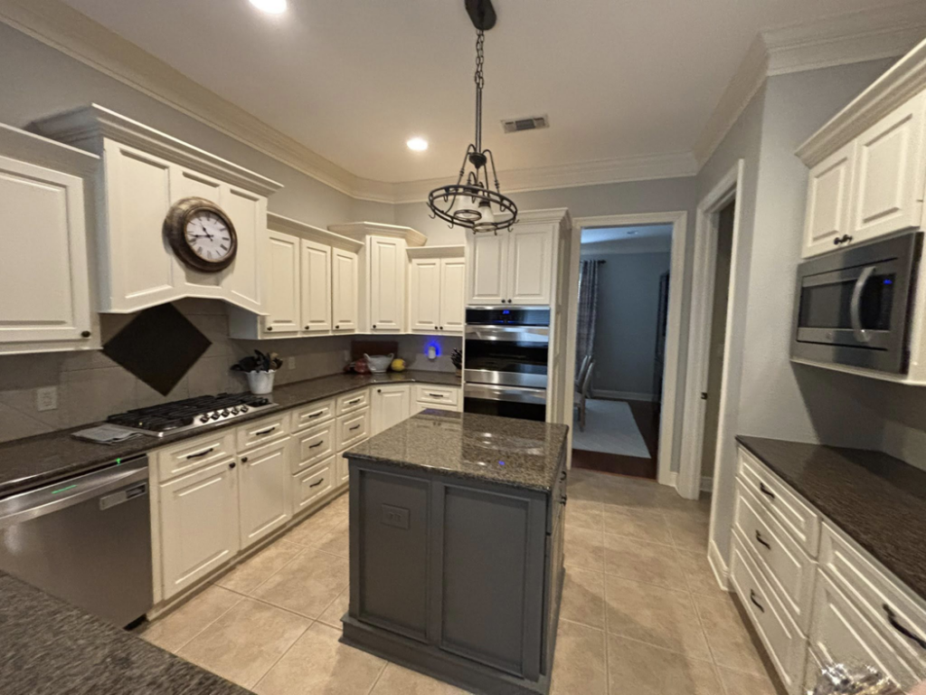 A sparkling clean modern kitchen with white cabinets and dark countertops by Cleaning by Design LLC in Frederick, MD.