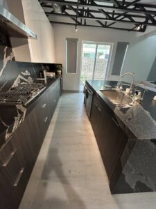 A clean, modern kitchen with dark cabinets and countertops, reflecting the professional cleaning by JG Clean Solutions in Henderson, NV.