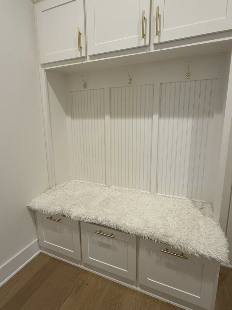 A clean and tidy mudroom bench with a soft rug, maintained by Global Provisions, AR in Fayetteville, AR.