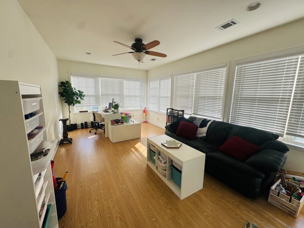 A spacious, clean, and organized living room with a desk and sofa by Consciously Cleared & Contained LLC in Elsmere, DE.