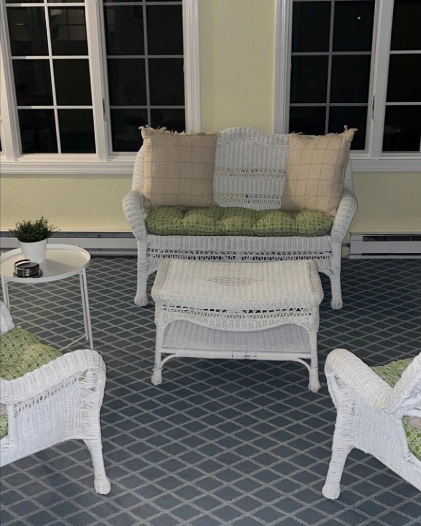 A clean outdoor patio or sunroom with white wicker furniture and a patterned rug, maintained by Make It Shine in Worcester, MA
