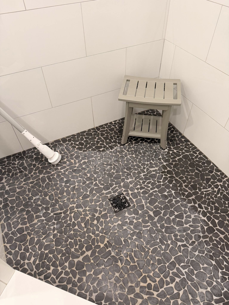 A sparkling clean pebble-tiled shower floor after professional cleaning by Jocelyn's Cleaning Services in Charlotte, NC.