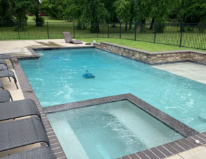 A pristine swimming pool with an attached spa and a robotic cleaner operating, serviced by AquaDocs in Dublin, OH.