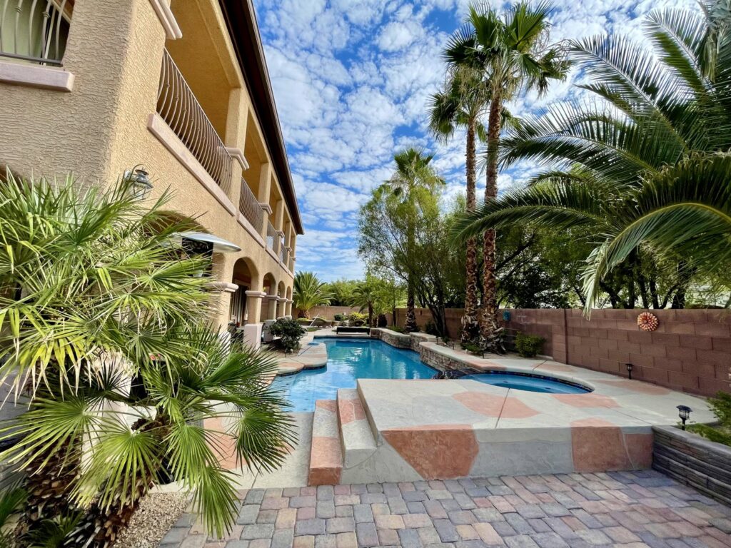 A clean swimming pool with a skimmer net and chemical bottle on the deck, after service by Priority Pools LV in Las Vegas, NV