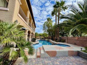 A clean swimming pool with a skimmer net and chemical bottle on the deck, after service by Priority Pools LV in Las Vegas, NV