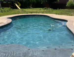 A clean swimming pool with a vacuum hose visible, indicating ongoing maintenance by AquaDocs in Dublin, OH.