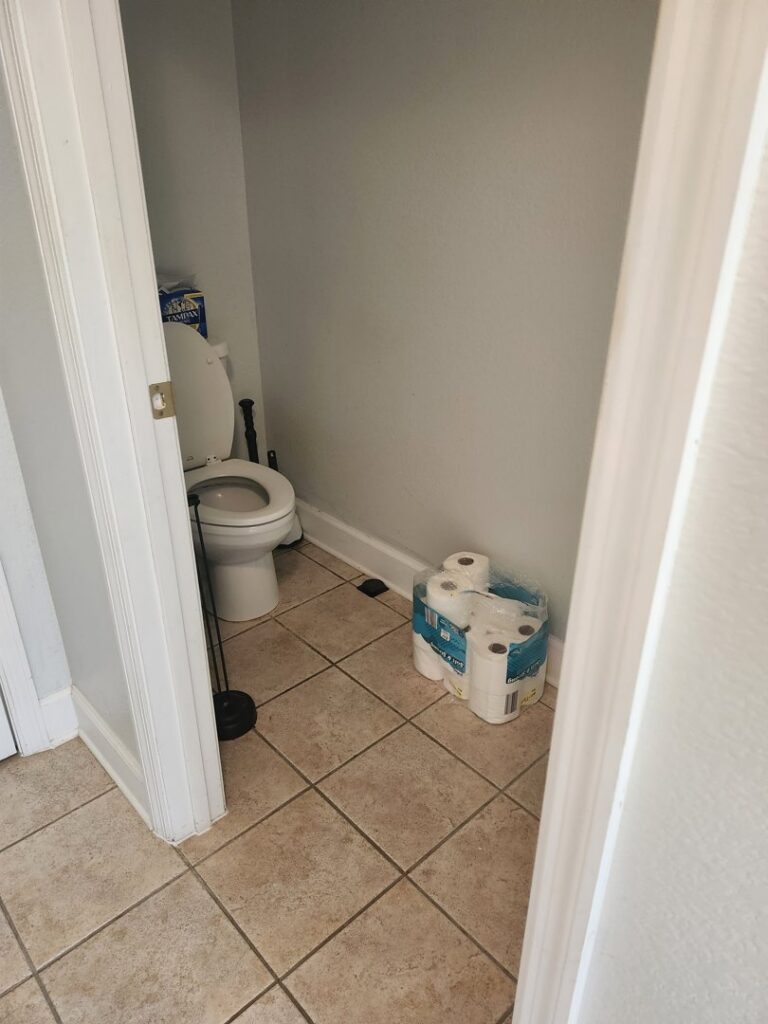 A clean powder room with a toilet and tiled floor, demonstrating the thorough cleaning services of S&M Cleaning Services 5 LLC in Cocoa, FL.