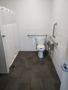 A spotless public restroom with a toilet and shower, expertly cleaned by Green Leaf Janitorial in Gilbert, AZ.