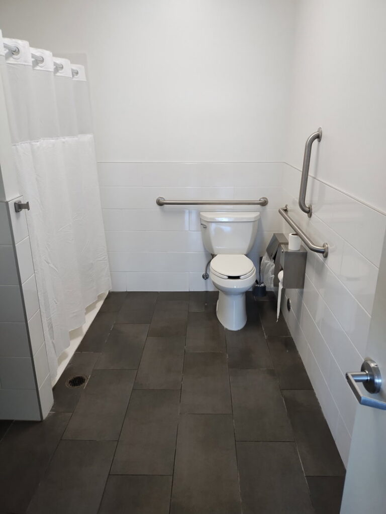 A spotless public restroom with a toilet and shower, expertly cleaned by Green Leaf Janitorial in Gilbert, AZ.