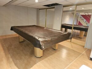 A clean recreation room featuring a covered pool table and polished wood floors, reflecting a house cleaning by Way Too Bright Services LLC in Rockford, IL.