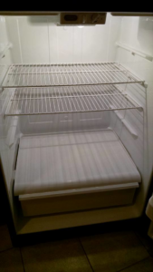 A clean and empty refrigerator interior, showcasing professional cleaning by Antioch Professional Cleaning in Manchester, NH.