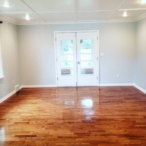 A clean, empty room with polished hardwood floors and elegant white double doors, cleaned by A To Zen in Lansing, MI.