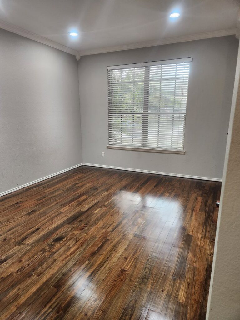 A freshly cleaned room with gleaming hardwood floors and clean blinds, a result of Rita's cleaning service in Fort Worth, TX.
