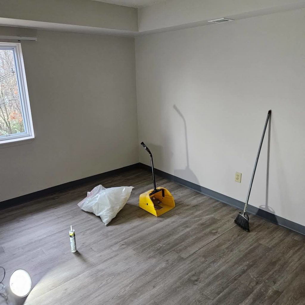 A freshly cleaned room with a broom and dustpan, showcasing janitorial services by Mary's Magic Touch Janitorial Services in Akron, OH.