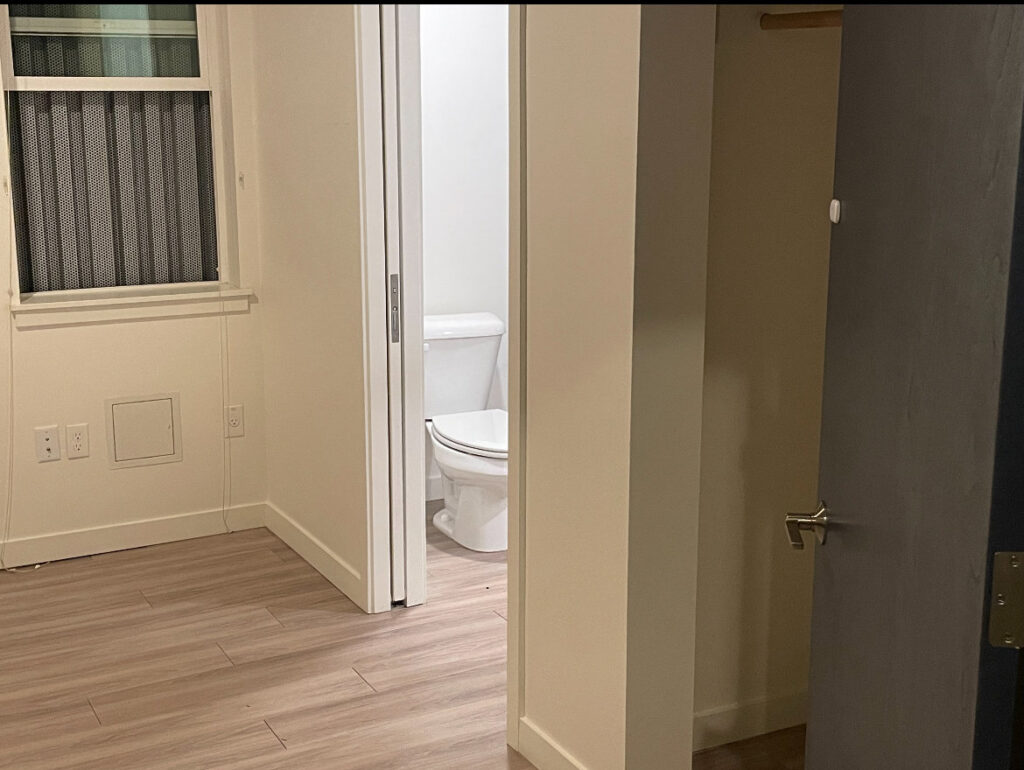 A freshly cleaned room with light wood flooring and a toilet visible in the adjacent bathroom, cleaned by Merriweather Cleaning and Laundry in Vancouver, WA.