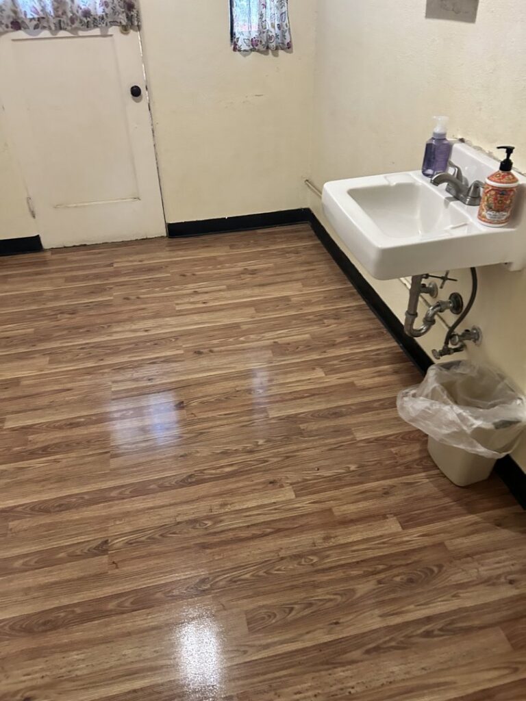 A clean room with shiny wooden floors and a wall-mounted sink, maintained by Green Leaf Janitorial in Gilbert, AZ.