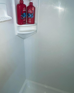 A sparkling clean white shower corner after professional cleaning by Stephie's From Dust To Glitter in Detroit, MI.
