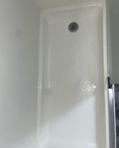A freshly cleaned white shower pan with a drain, sparkling after service from Stephie's From Dust To Glitter in Detroit, MI.