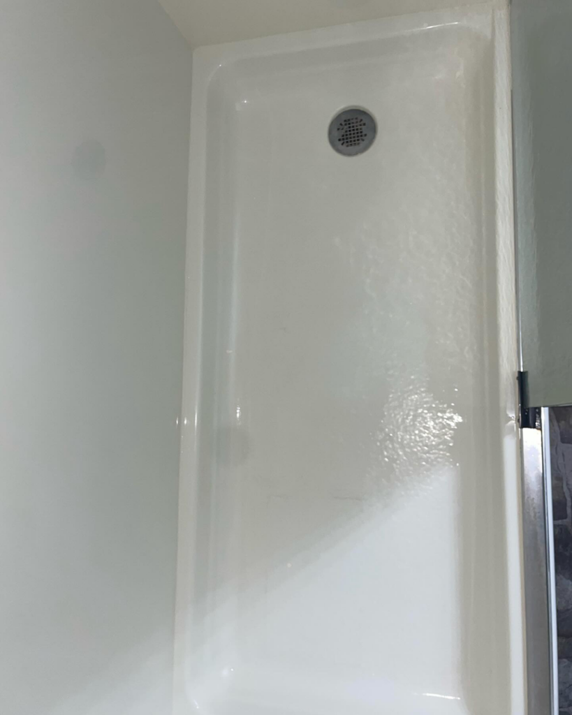A freshly cleaned white shower pan with a drain, sparkling after service from Stephie's From Dust To Glitter in Detroit, MI.