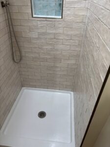 A sparkling clean shower stall with neatly tiled walls and a white base, cleaned by Cleaning Service Masters LLC in Escondido, CA