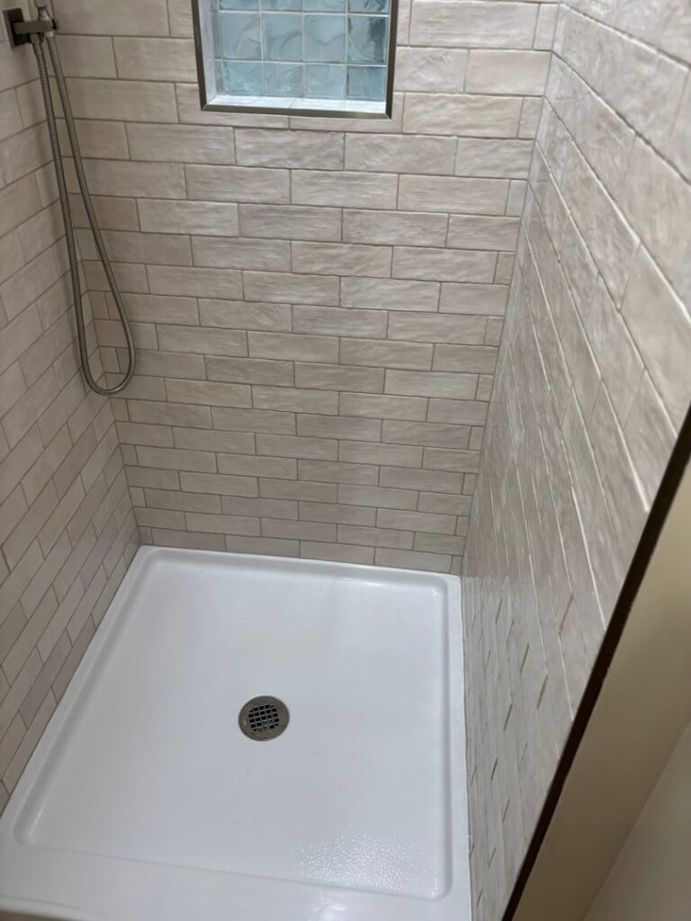 A sparkling clean shower stall with neatly tiled walls and a white base, cleaned by Cleaning Service Masters LLC in Escondido, CA