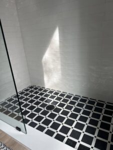 A sparkling clean shower with black and white tiled floor, showcasing the results of Nichole's Cleaning Service in Fort Wayne, IN
