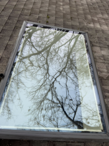 A sparkling clean skylight on a roof, reflecting trees and sky, after professional washing by Exterior Wash Pro LLC in Springdale, AR.