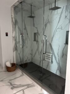 A clean and spacious glass shower enclosure with marble-patterned walls, expertly cleaned by JG Clean Solutions in Henderson, NV.
