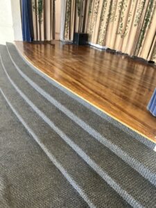 A clean stage with polished wooden floors and carpeted stairs, maintained by Green Leaf Janitorial in Gilbert, AZ.