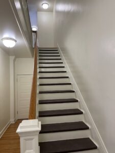 A clean staircase with dark wood treads and white risers, reflecting detailed cleaning services by 307 Maid in Cheyenne, WY.