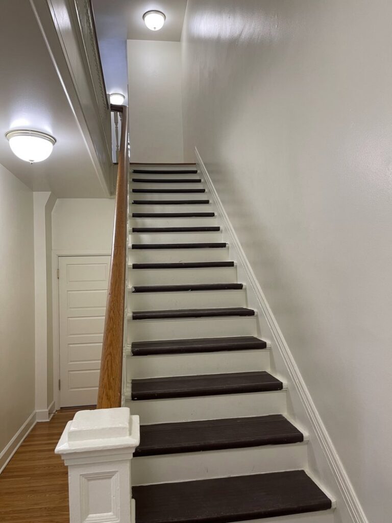 A clean staircase with dark wood treads and white risers, reflecting detailed cleaning services by 307 Maid in Cheyenne, WY.