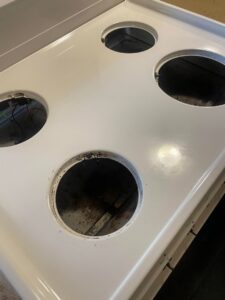 A sparkling clean white stove top with burners removed, showcasing deep cleaning by Skedaddle Cleaning Services in Eufaula, AL.
