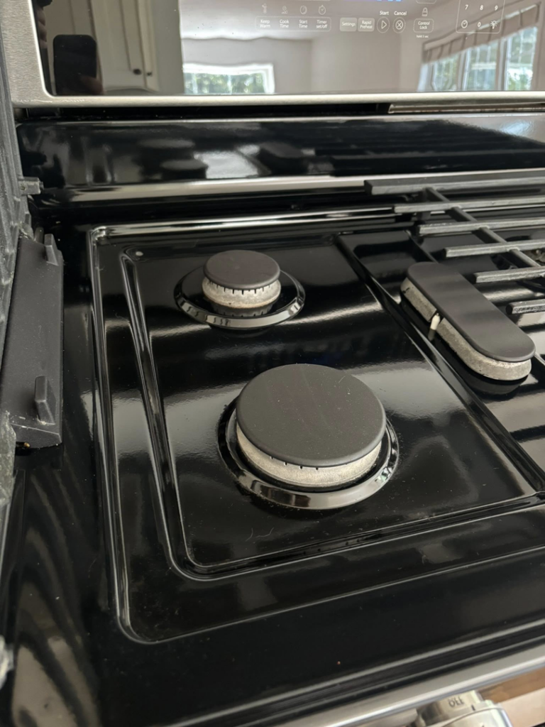 A shiny, clean stovetop with burners after professional cleaning by Tidy Townhouses in Manchester, NH.
