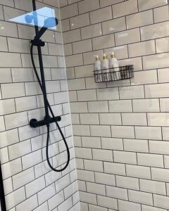 A pristine shower with white subway tiles and black fixtures, showcasing a professionally cleaned bathroom by Pretty & Polished Cleaning Services in Sandy, OR.