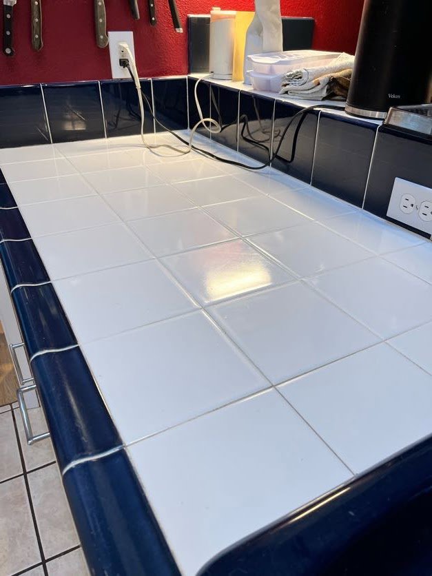 A spotless tiled kitchen counter with dark blue trim, cleaned by Sage & Soap Cleaning Co in Kansas City, MO.